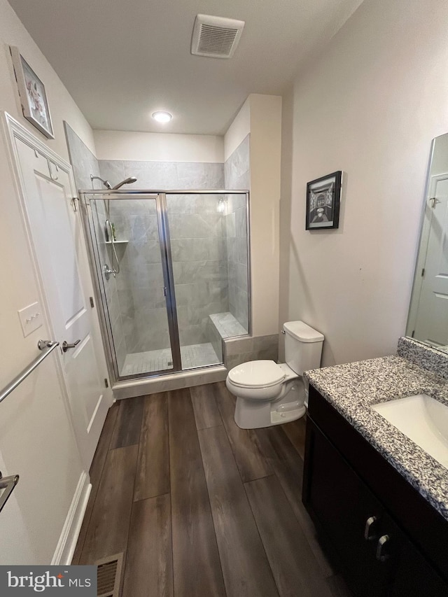 full bath featuring vanity, wood finished floors, visible vents, and a stall shower