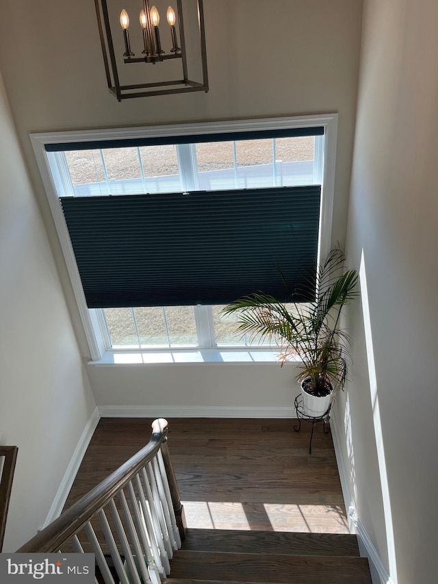 staircase with a chandelier, baseboards, and wood finished floors