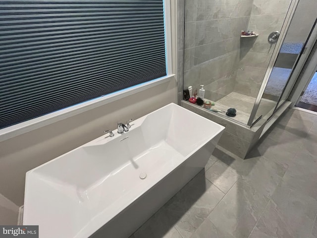 bathroom featuring a stall shower and a freestanding bath