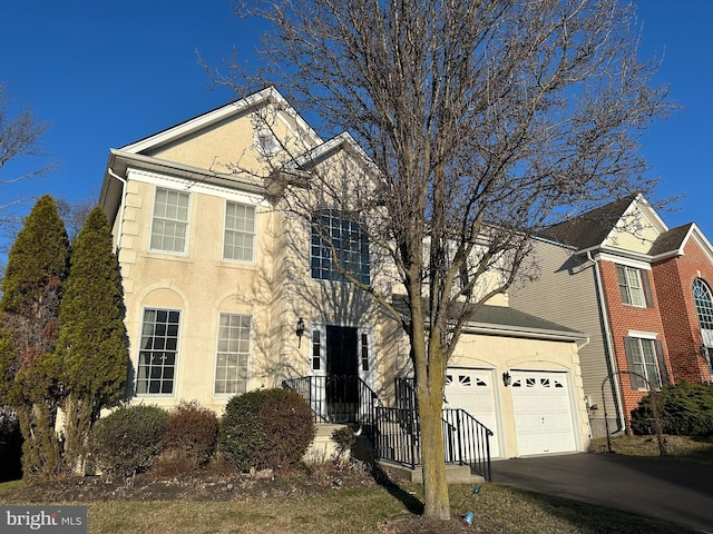 view of front facade with concrete driveway, an attached garage, and stucco siding