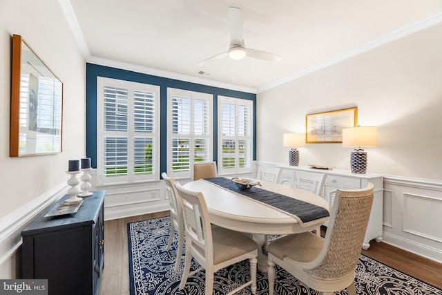 dining room with crown molding, a ceiling fan, visible vents, and dark wood-type flooring