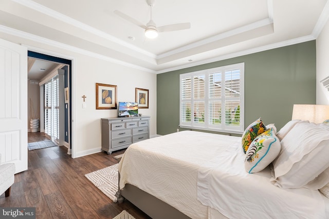 bedroom featuring baseboards, ornamental molding, dark wood-style floors, a raised ceiling, and a ceiling fan