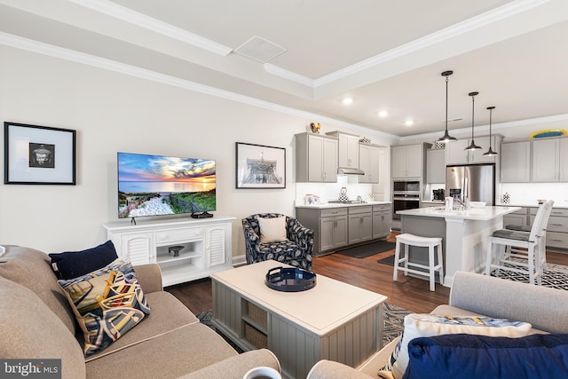 living area featuring recessed lighting, visible vents, dark wood-style floors, and ornamental molding