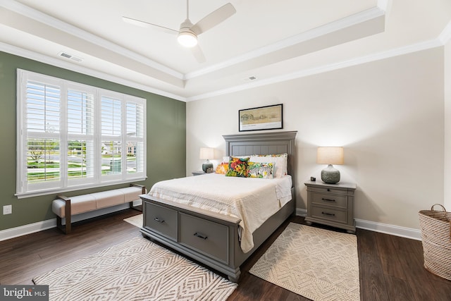 bedroom featuring dark wood-style floors, baseboards, visible vents, a tray ceiling, and crown molding