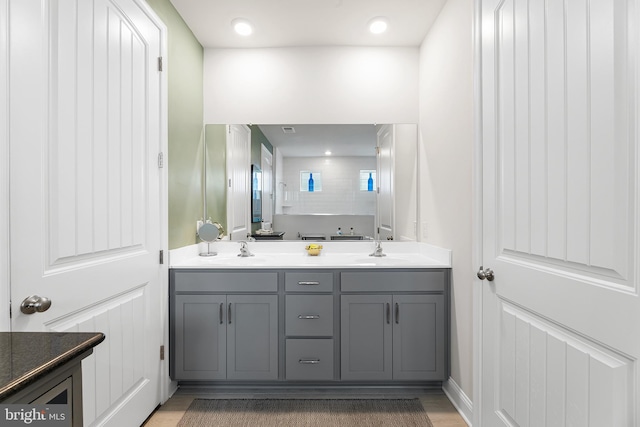 full bath with double vanity, wood finished floors, and a sink