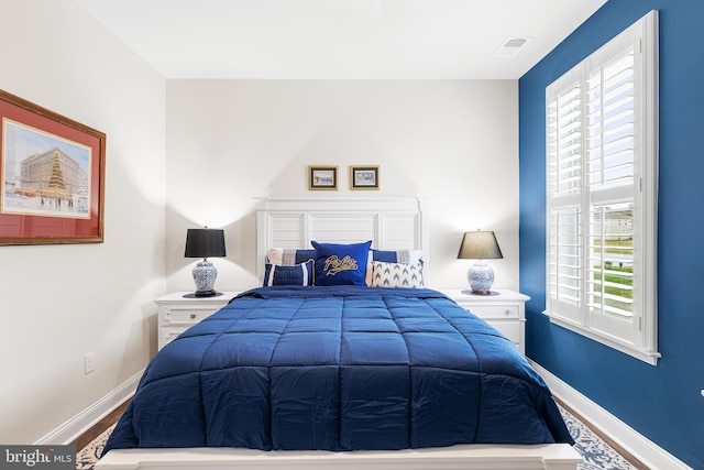 bedroom with visible vents, baseboards, and wood finished floors