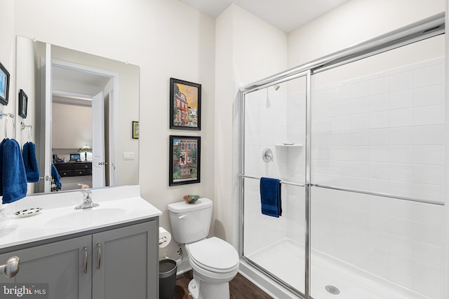 bathroom with vanity, wood finished floors, a shower stall, ensuite bathroom, and toilet