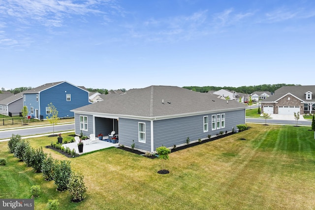 rear view of house featuring a patio area, a residential view, a shingled roof, and a yard