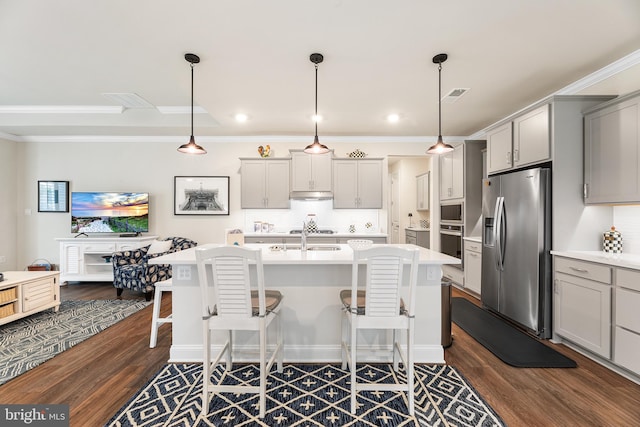 kitchen featuring gray cabinets, stainless steel appliances, a breakfast bar area, light countertops, and dark wood-style flooring