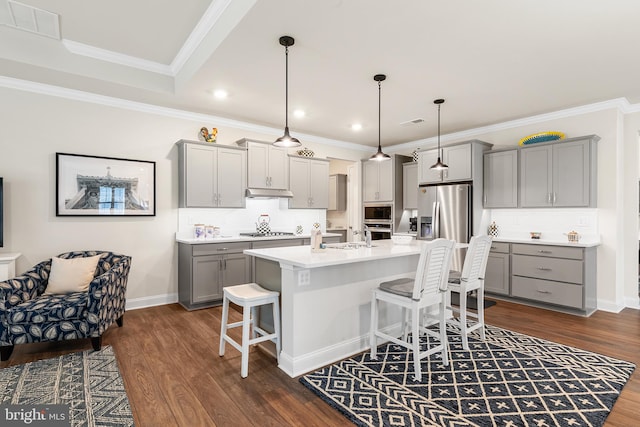 kitchen with gray cabinets, a kitchen breakfast bar, stainless steel appliances, and dark wood-style flooring