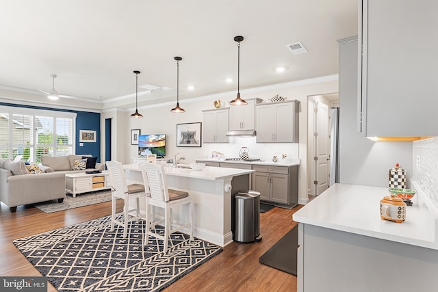 kitchen with visible vents, a breakfast bar, gray cabinetry, under cabinet range hood, and open floor plan