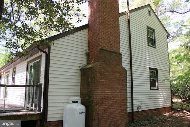 view of property exterior featuring crawl space, a chimney, and a deck