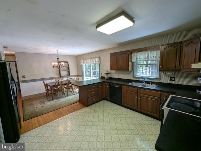 kitchen with dark countertops, a sink, black appliances, a peninsula, and a chandelier