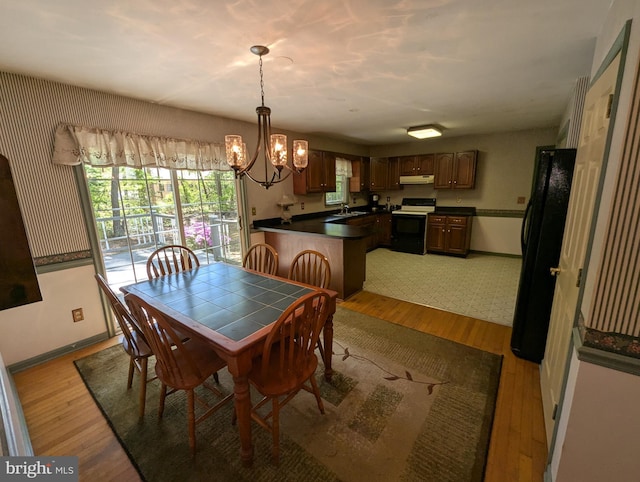 dining area with light wood-type flooring, baseboards, and a chandelier
