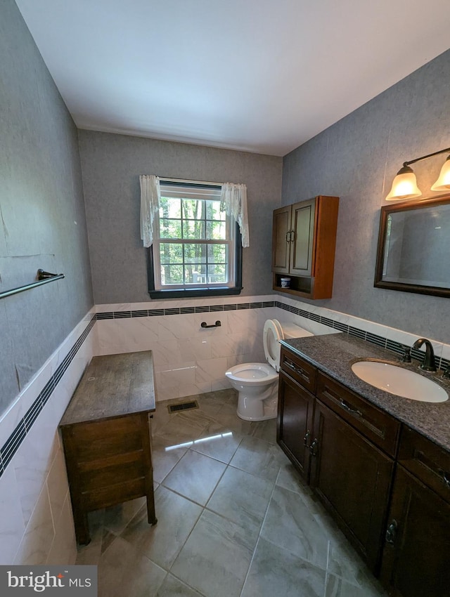 bathroom featuring toilet, tile walls, visible vents, and vanity