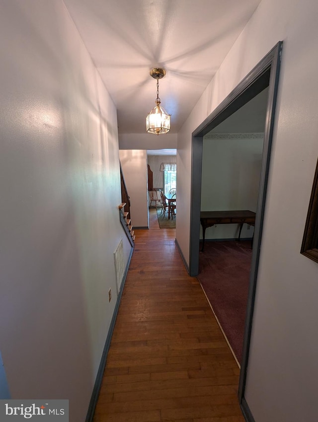 corridor with visible vents, a chandelier, and hardwood / wood-style floors