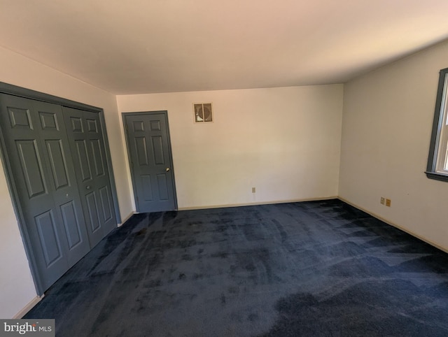 unfurnished room with baseboards and dark colored carpet