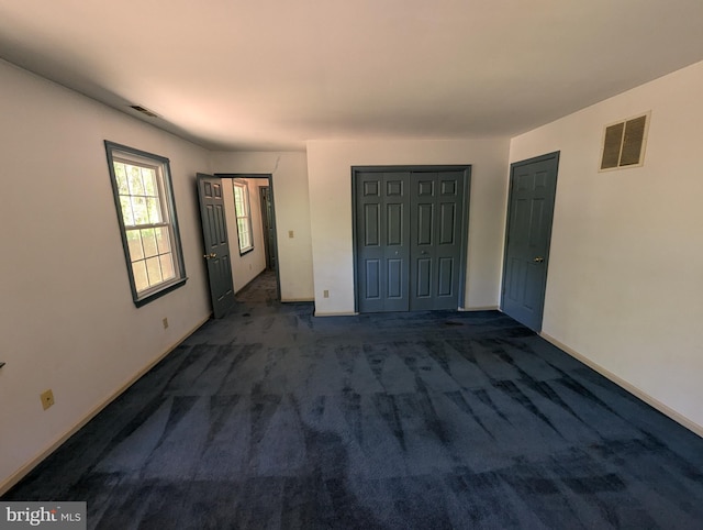 unfurnished bedroom featuring baseboards, carpet, a closet, and visible vents