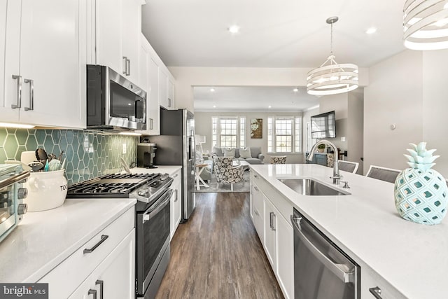 kitchen featuring backsplash, open floor plan, appliances with stainless steel finishes, dark wood-style floors, and a sink