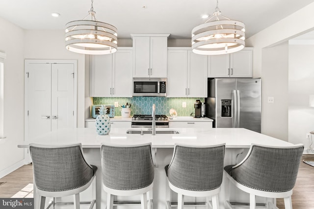 kitchen featuring tasteful backsplash, a notable chandelier, appliances with stainless steel finishes, and a sink