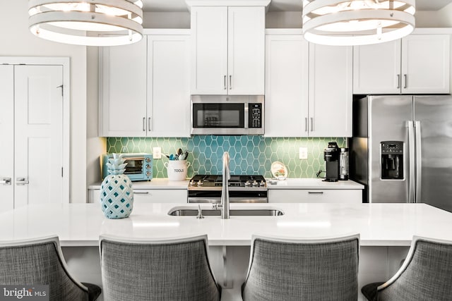 kitchen featuring a toaster, appliances with stainless steel finishes, light countertops, and decorative backsplash