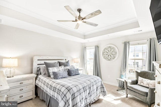 bedroom with a tray ceiling, light carpet, and multiple windows