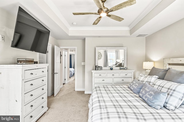 bedroom with a tray ceiling, light colored carpet, visible vents, and baseboards