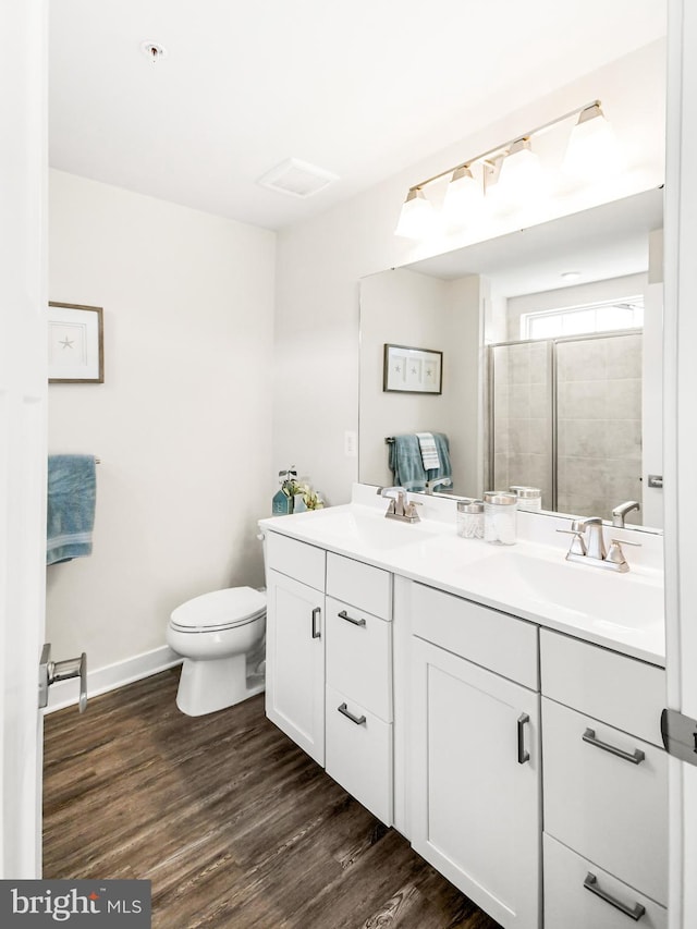 full bath with double vanity, wood finished floors, a stall shower, and a sink