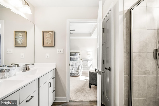 ensuite bathroom featuring baseboards, double vanity, a tile shower, ensuite bathroom, and wood finished floors