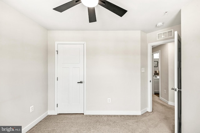 unfurnished bedroom featuring visible vents, light carpet, baseboards, and a ceiling fan