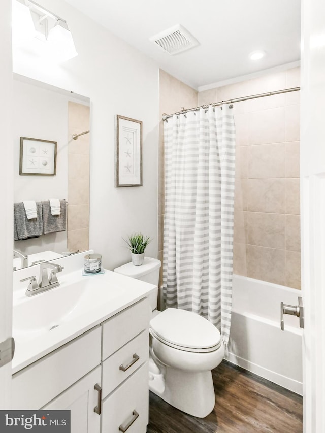 bathroom featuring visible vents, toilet, shower / tub combo with curtain, wood finished floors, and vanity