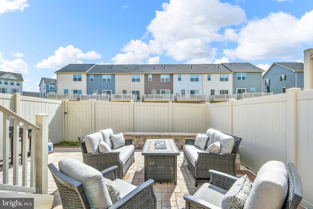 view of patio / terrace with an outdoor living space with a fire pit, a gate, a fenced backyard, and a residential view