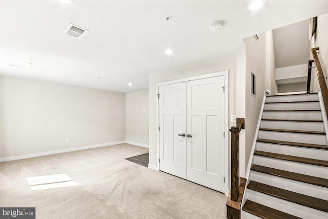 below grade area with visible vents, baseboards, carpet, and stairway