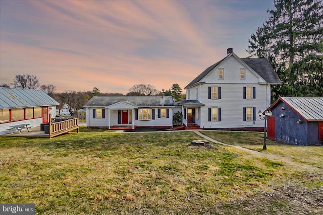 view of front of house featuring a yard, a storage shed, an outdoor structure, and a chimney