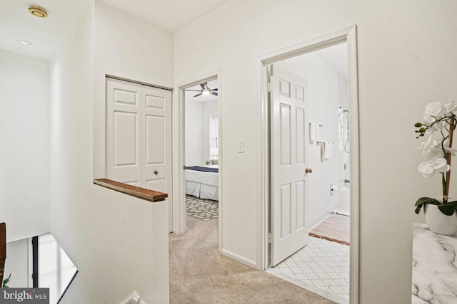 corridor featuring an upstairs landing and light colored carpet