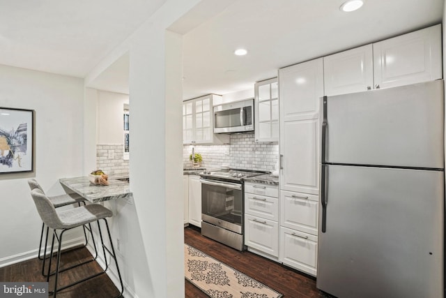 kitchen featuring backsplash, dark wood-type flooring, recessed lighting, stainless steel appliances, and white cabinetry