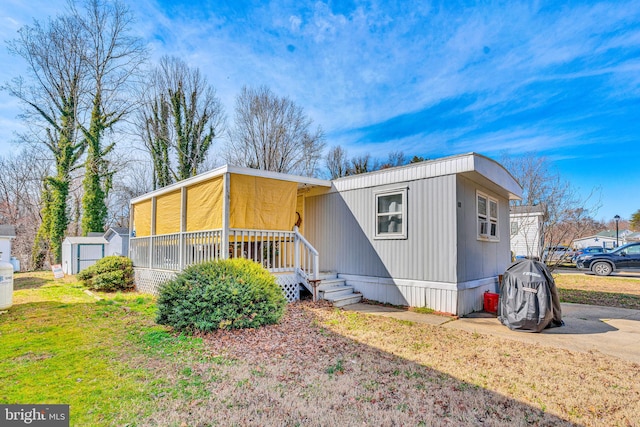 manufactured / mobile home with concrete driveway and a front lawn