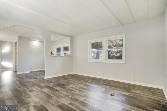 spare room featuring visible vents, baseboards, and dark wood-style flooring