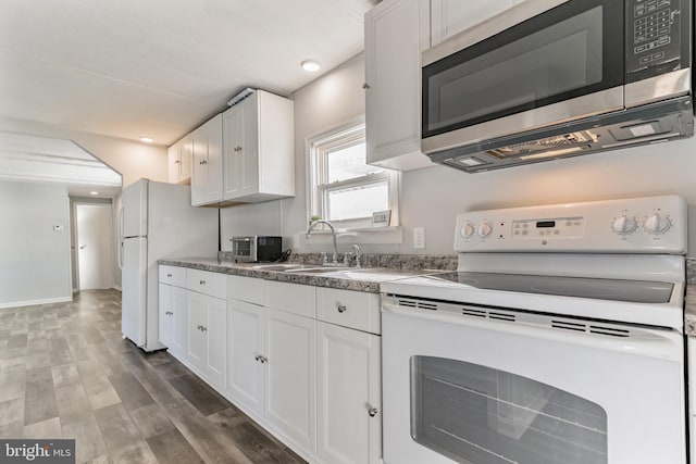 kitchen featuring white appliances, white cabinets, wood finished floors, and a sink