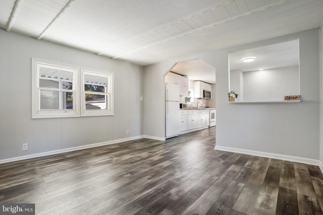 unfurnished living room featuring a sink, baseboards, arched walkways, and dark wood-style flooring