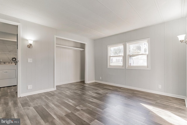 unfurnished bedroom with a closet, baseboards, washer / dryer, and wood finished floors