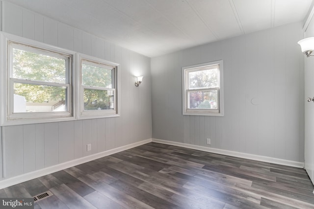 empty room with dark wood-type flooring, baseboards, and visible vents