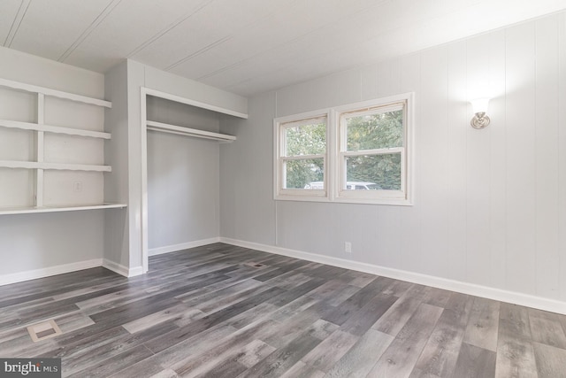 unfurnished bedroom featuring a closet, baseboards, and dark wood-type flooring