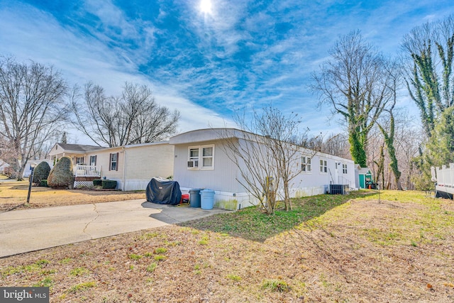 exterior space featuring central air condition unit, a lawn, and driveway