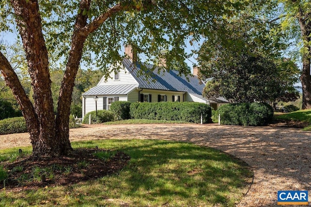 view of front of house featuring metal roof, a chimney, and a standing seam roof