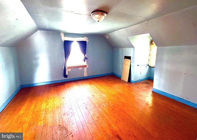 additional living space featuring vaulted ceiling, baseboards, and hardwood / wood-style floors