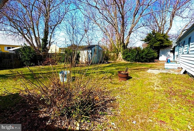 view of yard featuring a storage shed, an outdoor structure, and fence