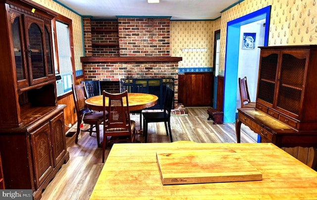 dining space with a brick fireplace, wood finished floors, and ornamental molding