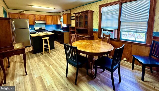 kitchen with a kitchen island, appliances with stainless steel finishes, wainscoting, and wallpapered walls