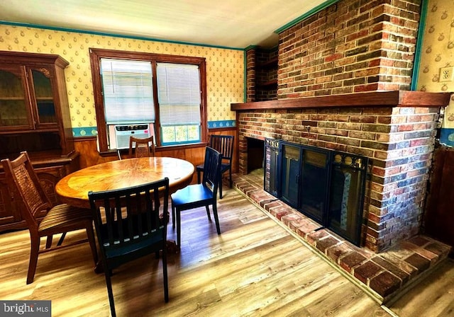 dining room with wallpapered walls, a fireplace, and wainscoting